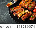 Hot grilled spare ribs from a summer BBQ served on a plate with sauce. Top view. Copy space 143280074