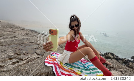 Female holding bright device near rocks with scenic background Female holding bright device near rocks with scenic background 143280243
