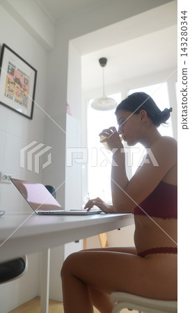 Young lady takes break enjoying her beverage while working remotely Young lady takes break enjoying her beverage while working remotely 143280344