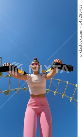 Caucasian female athlete engaging in intense suspension exercise outdoors Caucasian female athlete engaging in intense suspension exercise outdoors 143280413