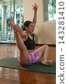 Woman practicing yoga with extended leg indoors 143281410