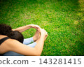 Woman practicing yoga stretching forward bend outdoors on grass 143281415