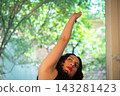 Woman reaching up towards natural light and green trees 143281423