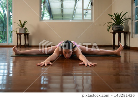 Woman practicing yoga wide angle seated forward bend Woman practicing yoga wide angle seated forward bend 143281426