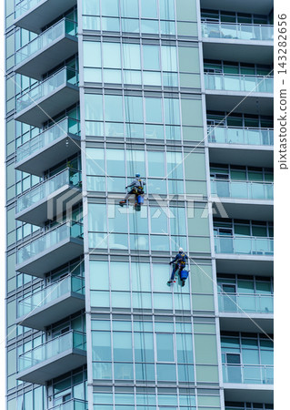 Window Cleaners Working on Modern Highrise Glass Building Window Cleaners Working on Modern Highrise Glass Building 143282656