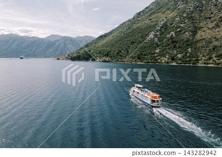 Tourist boat cruising in scenic mountain bay landscape Tourist boat cruising in scenic mountain bay landscape 143282942