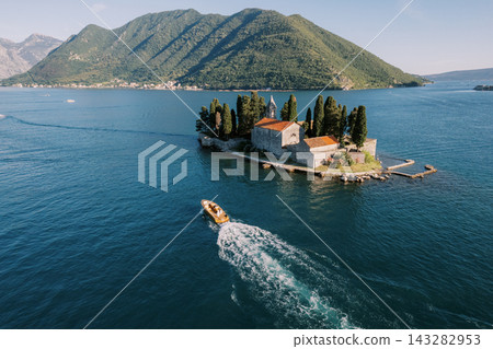 Aerial perspective capturing island chapel with boat and mountain backdrop Aerial perspective capturing island chapel with boat and mountain backdrop 143282953