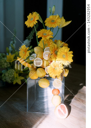 Creative Floral and Citrus Arrangement in Clear Vase on Wooden Table Creative Floral and Citrus Arrangement in Clear Vase on Wooden Table 143282954