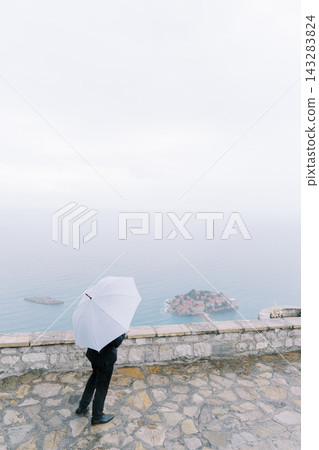 Single traveler navigates seaside walkway with distant vessels and small islands visible Single traveler navigates seaside walkway with distant vessels and small islands visible 143283824
