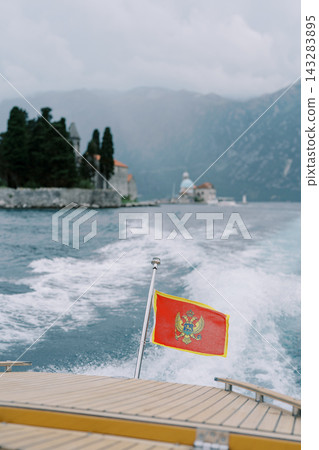 Peaceful voyage across mountain lake with fluttering flag and misty island views Peaceful voyage across mountain lake with fluttering flag and misty island views 143283895
