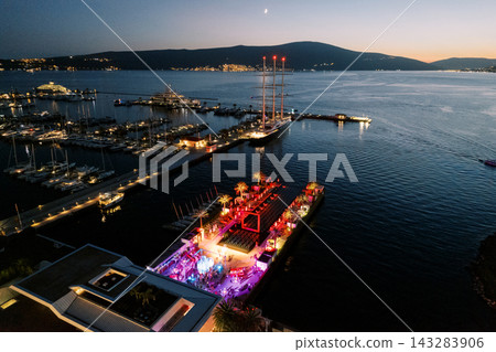 Porto Montenegro marina at dusk with superyachts and illuminated waterfront Porto Montenegro marina at dusk with superyachts and illuminated waterfront 143283906
