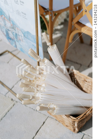 White Paper Parasols in Wicker Basket at Outdoor Event White Paper Parasols in Wicker Basket at Outdoor Event 143284218