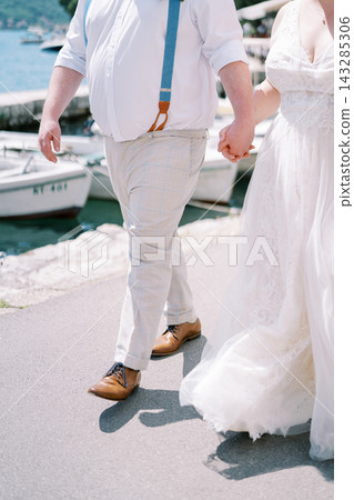 Couple by marina water. Sunlit romantic walk on shoreline with boats and smiling couple 143285306