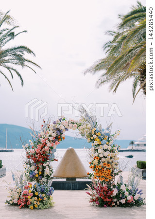 Intimate wedding setup on coast with pastel floral arch and tranquil water background Intimate wedding setup on coast with pastel floral arch and tranquil water background 143285440