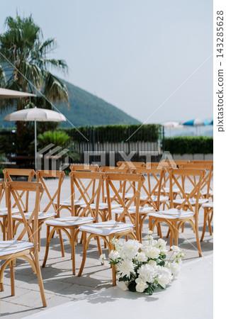 Coastal wedding setup. Charming seaside ceremony featuring floral aisles and mountain views Coastal wedding setup. Charming seaside ceremony featuring floral aisles and mountain views 143285628
