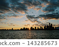 Tranquil City Silhouette During Dusk With Glowing Clouds And Peaceful River Reflection 143285673