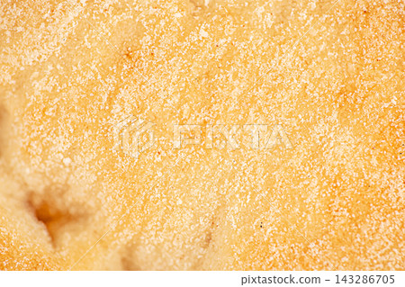 Close up of golden textured surface with fine sugar crystals and soft irregular contours creating an abstract warm yellow background, macro food texture 143286705
