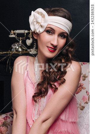 Elegant young woman and girl sitting in a floral armchair in 1920s style Elegant young woman and girl sitting in a floral armchair in 1920s style 143286928