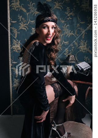 Elegant young woman and girl in 1920s vintage style with silver heels and open back dress Elegant young woman and girl in 1920s vintage style with silver heels and open back dress 143286938