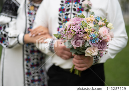 the bride and groom are holding hands with a bouquet of flowers and in traditional Ukrainian clothes 143287329
