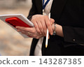 Close-up of a person holding a notebook and pen during a professional event 143287385