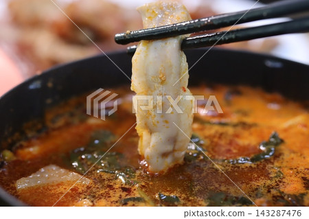 Chopsticks Holding Dumpling in Spicy Soup Chopsticks Holding Dumpling in Spicy Soup 143287476