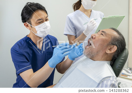 一位牙醫正在為一位70多歲的老人做檢查。 一位牙醫正在為一位70多歲的老人做檢查。 143288362
