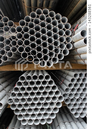 Bundled metal pipes stacked in a hexagonal honeycomb pattern on a storage rack. Bundled metal pipes stacked in a hexagonal honeycomb pattern on a storage rack. 143288561