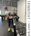 Functional Workout on Exercise Bike in Gym. European woman pedaling exercise bike in gym, personal crossfit training, weightlifting. healthy lifestyle concept 143288641