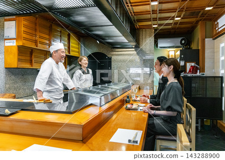 一對情侶在壽司店與壽司師傅聊天。 143288900