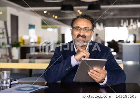 Portrait of smiling businessman using digital tablet in office 143289505