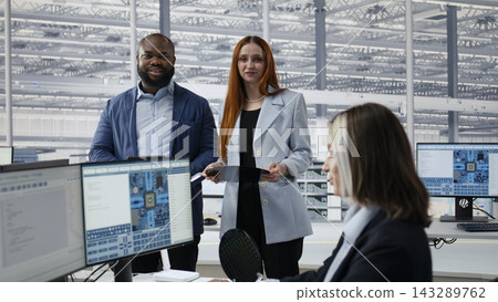Portrait of smiling engineering team examining semiconductor substrate inside modern microchip research facility office. Happy multiethnic RD workspace colleagues inspect silicon wafer, camera A Portrait of smiling engineering team examining semiconductor substrate inside modern microchip research facility office. Happy multiethnic RD workspace colleagues inspect silicon wafer, camera A 143289762