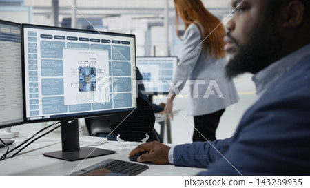 Technician in microchip factory RD workspace optimizing production with PC software. African american employee in office using computer to improve semiconductors processing efficiency, camera A Technician in microchip factory RD workspace optimizing production with PC software. African american employee in office using computer to improve semiconductors processing efficiency, camera A 143289935