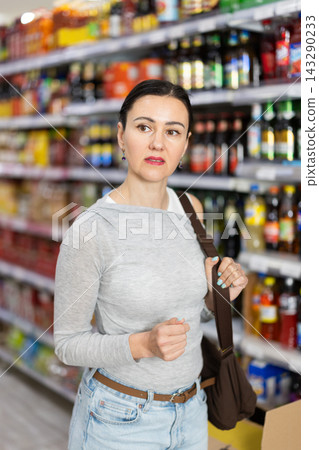 In food store, woman looking for something on shelf of showcase 143290233