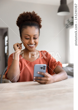 Cheerful African woman reading message on her smartphone Cheerful African woman reading message on her smartphone 143290367