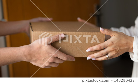 Close up cropped shot man woman hands holding cardboard box Close up cropped shot man woman hands holding cardboard box 143290422