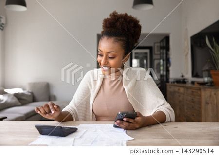 Woman calculates personal finances at home using calculator and smartphone Woman calculates personal finances at home using calculator and smartphone 143290514