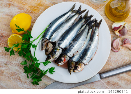 Raw sardines on plate with greens, lemon and garlic 143290541