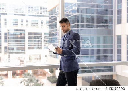 Male company owner planning projects on tablet in glass office Male company owner planning projects on tablet in glass office 143290590