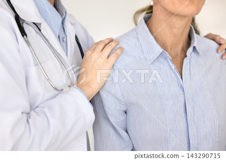 Female doctor reassuring woman patient with supportive hand on shoulder 143290715