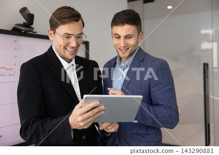 Happy male managers reading good news on digital tablet screen Happy male managers reading good news on digital tablet screen 143290881