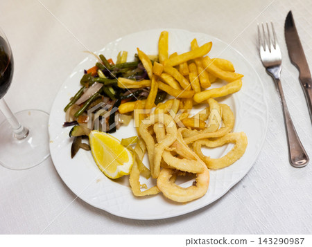 Deep-fried coated squid rings with fries and sauteed vegetables Deep-fried coated squid rings with fries and sauteed vegetables 143290987