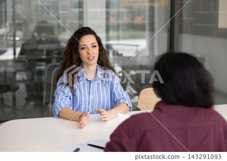 Young adult woman discussing project, planning strategy, speaking with colleague Young adult woman discussing project, planning strategy, speaking with colleague 143291093