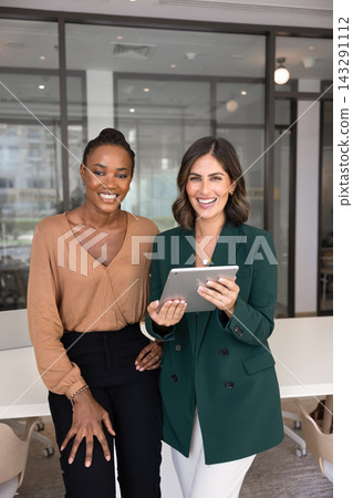 Confident businesswomen standing with digital tablet in office 143291112