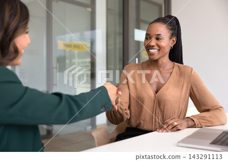Smiling businesswoman shaking hands after successful meeting Smiling businesswoman shaking hands after successful meeting 143291113