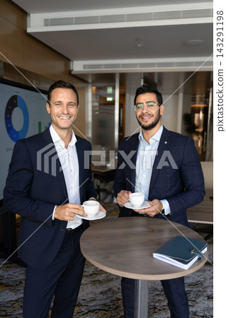 Smiling multiethnic men colleagues holding cups during coffee break Smiling multiethnic men colleagues holding cups during coffee break 143291198