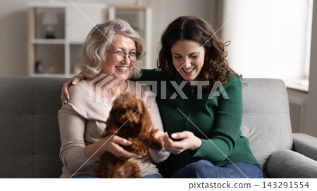 Granddaughter and grandmother enjoy conversation sit on couch with dog Granddaughter and grandmother enjoy conversation sit on couch with dog 143291554