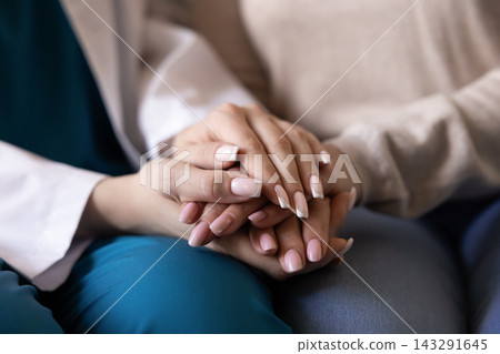 Closeup of caregiver doctor holding hand of senior woman patient 143291645