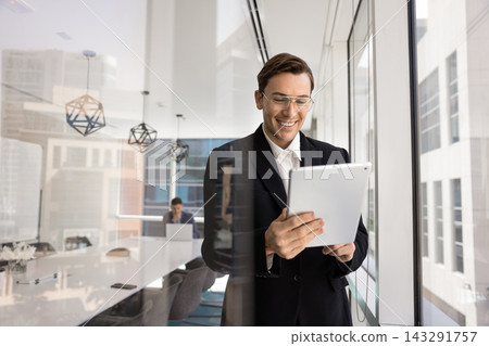 Smiling corporate employee interacting with tablet device at modern boardroom 143291757