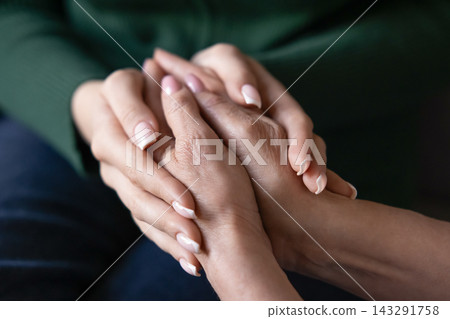 Closeup two women holding hands showing support or compassion Closeup two women holding hands showing support or compassion 143291758
